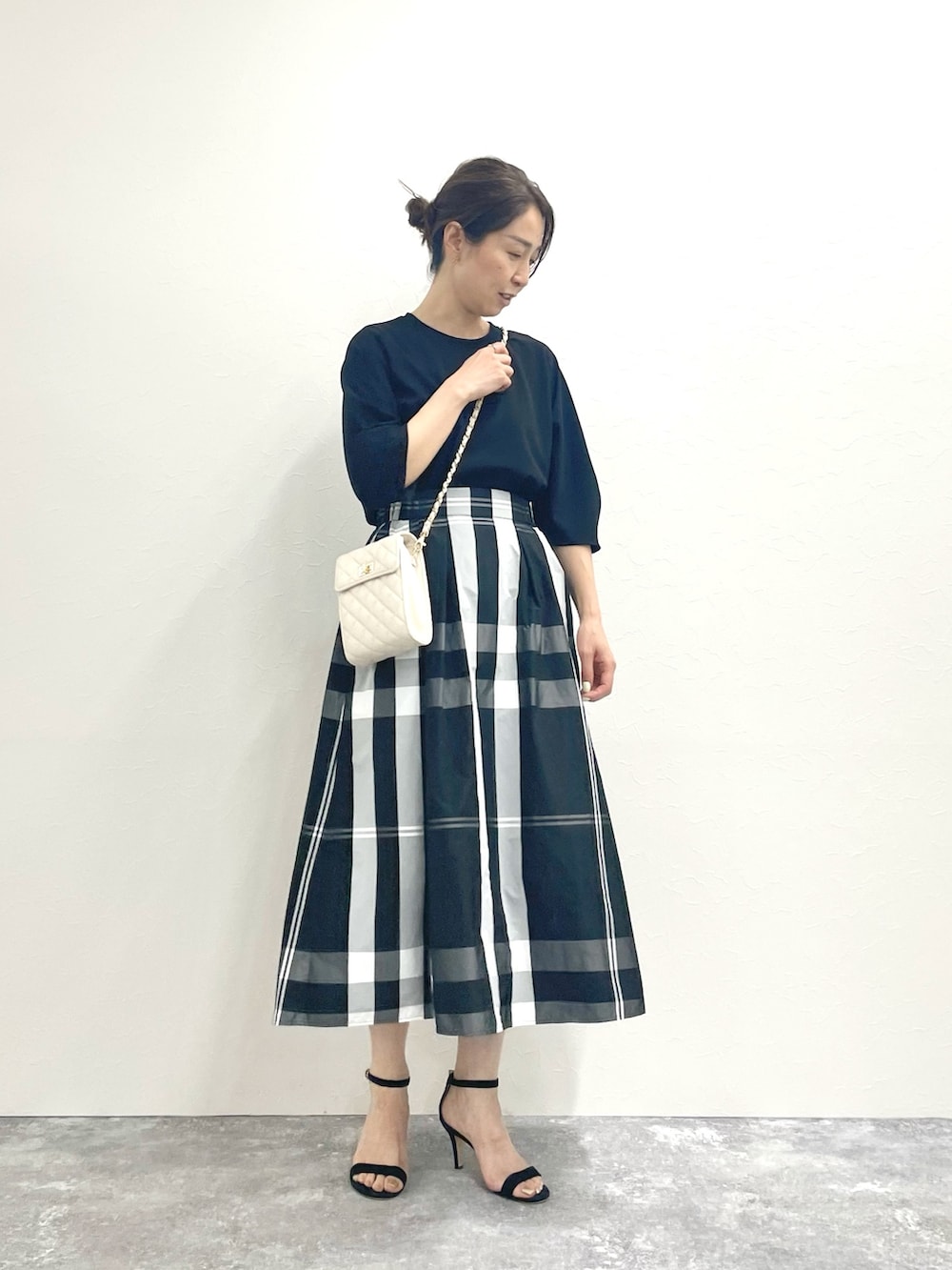 ブラック系のTシャツ/カットソー、ホワイト系のショルダーバッグ、ブラック系のスカートを着用したレディースの春コーディネートの2枚目の写真