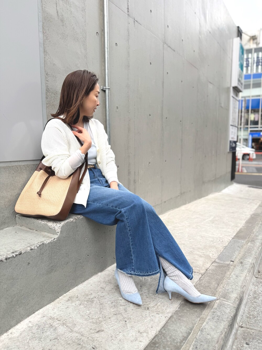 ブルー系のデニムパンツ、ブラウン系のショルダーバッグ、ホワイト系のカーディガン/ボレロを着用したレディースの春コーディネートの4枚目の写真