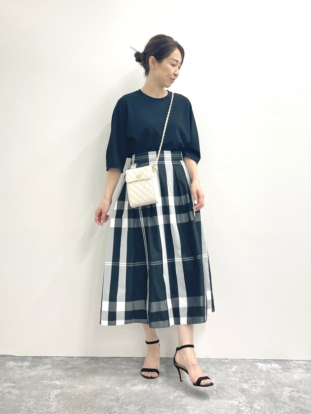 ブラック系のTシャツ/カットソー、ホワイト系のショルダーバッグ、ブラック系のスカートを着用したレディースの春コーディネートの5枚目の写真