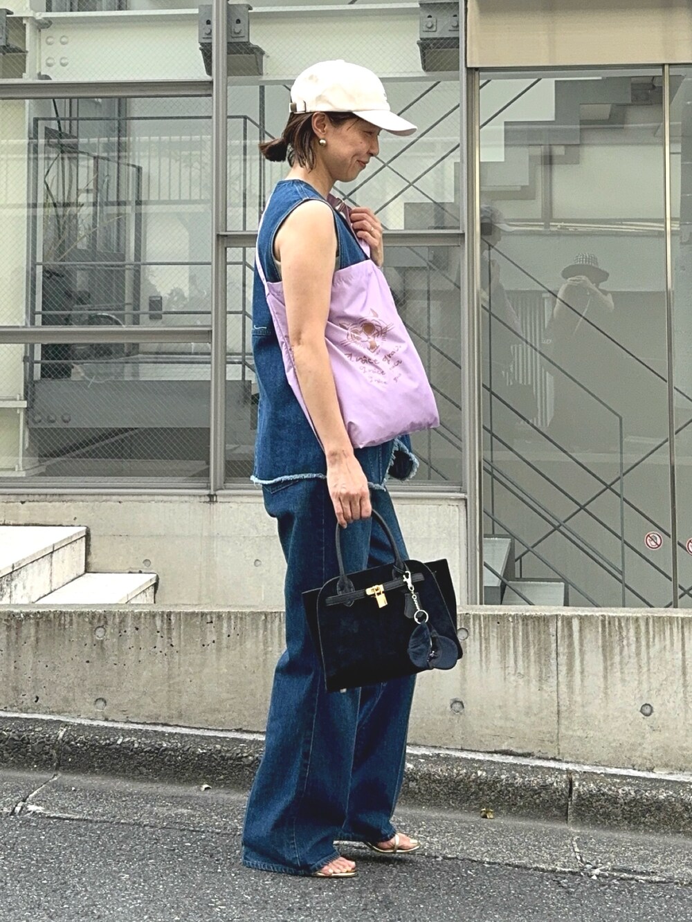 ブルー系のデニムパンツ、ブルー系のベスト、ブラック系のトートバッグを着用したレディースの夏コーディネートの4枚目の写真