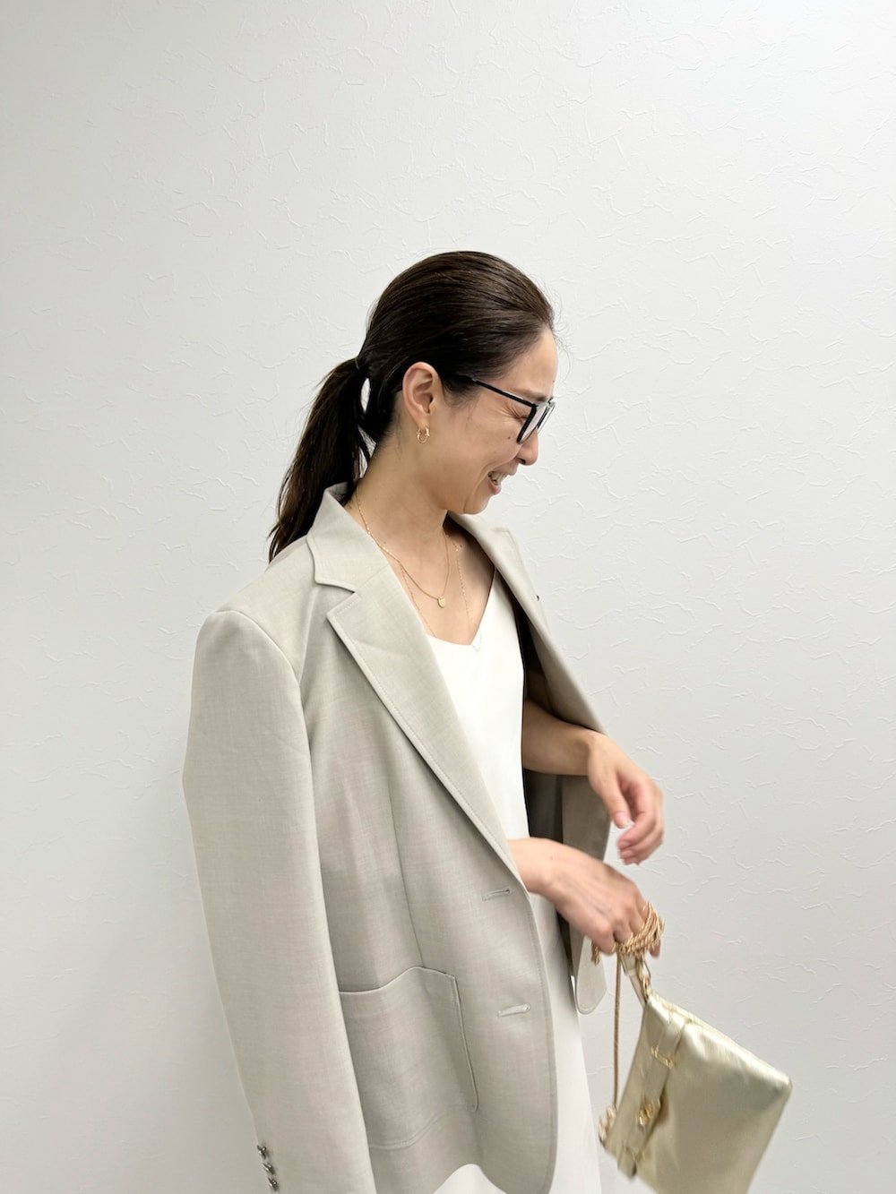 ベージュ系のテーラードジャケット、ベージュ系のタンクトップ、ホワイト系のスカートを着用したレディースの夏コーディネートの5枚目の写真