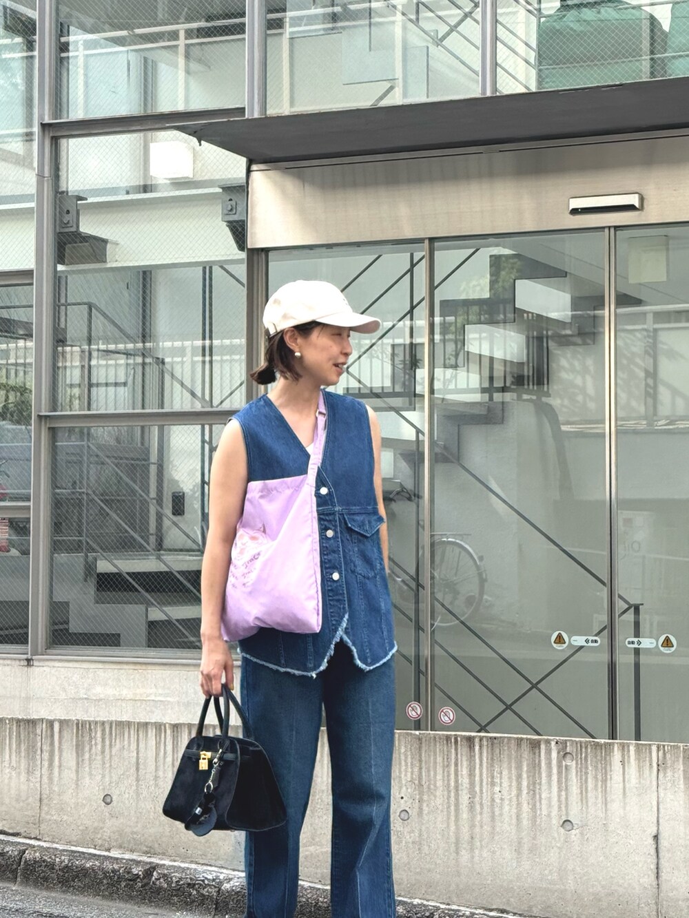 ブルー系のデニムパンツ、ブルー系のベスト、ブラック系のトートバッグを着用したレディースの夏コーディネートの5枚目の写真