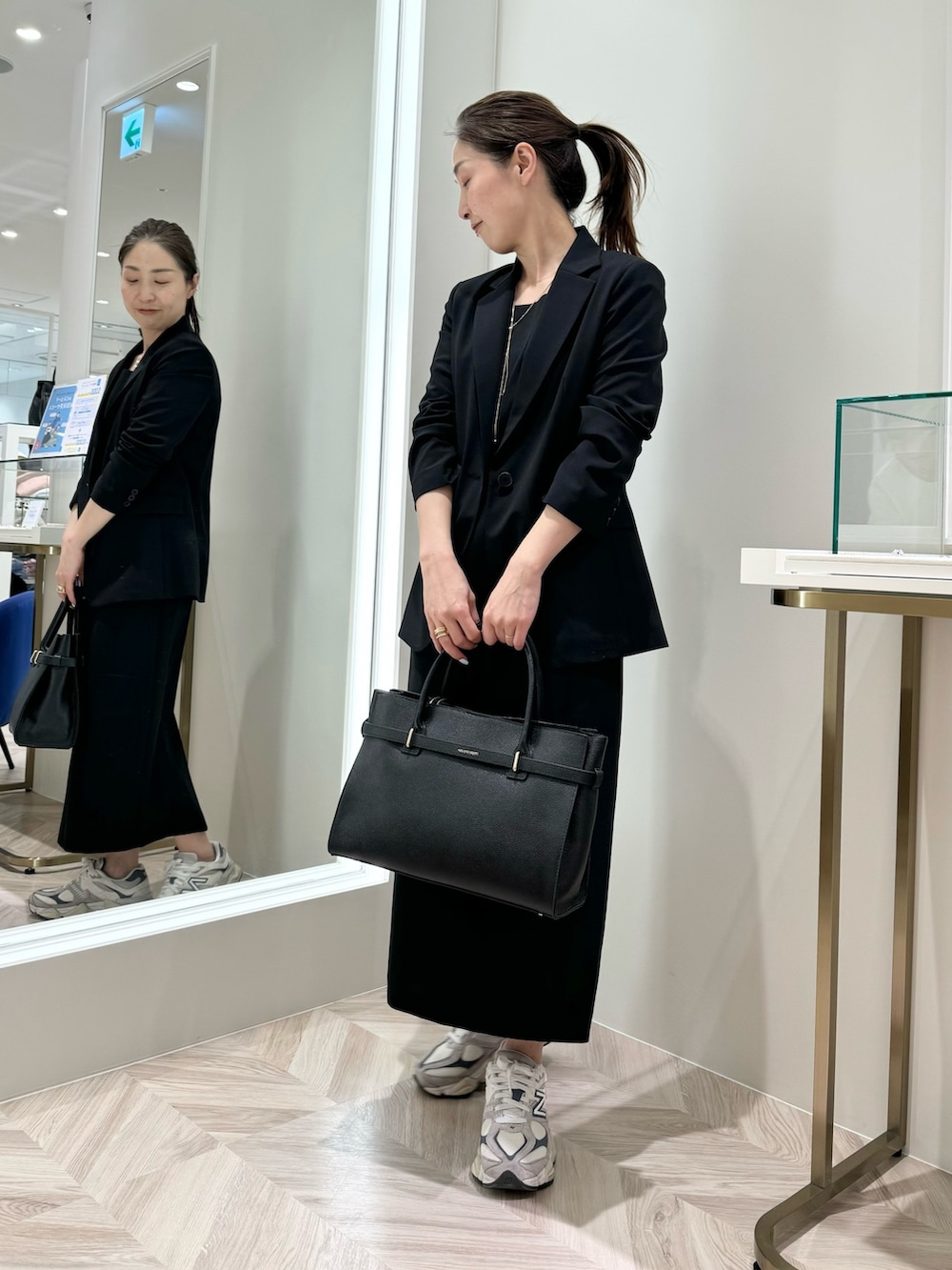 ブラック系のワンピース、ブラック系のトートバッグ、ブラック系のテーラードジャケットを着用したレディースの春コーディネートの5枚目の写真