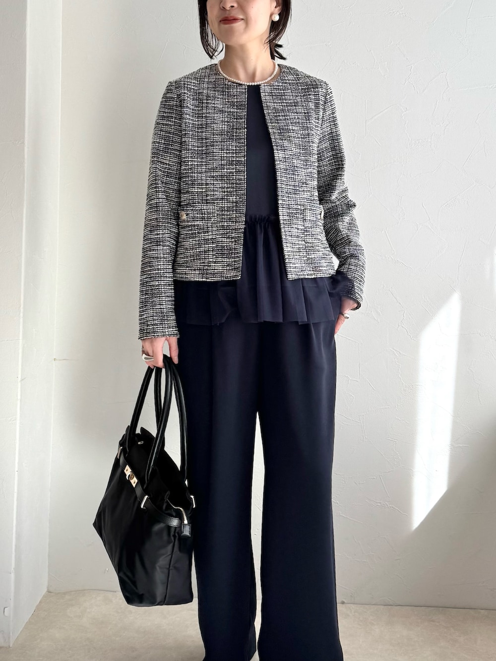 ブラック系のノーカラージャケット、ブルー系のシャツ/ブラウス、ブラック系のトートバッグを着用したレディースの春コーディネートの9枚目の写真