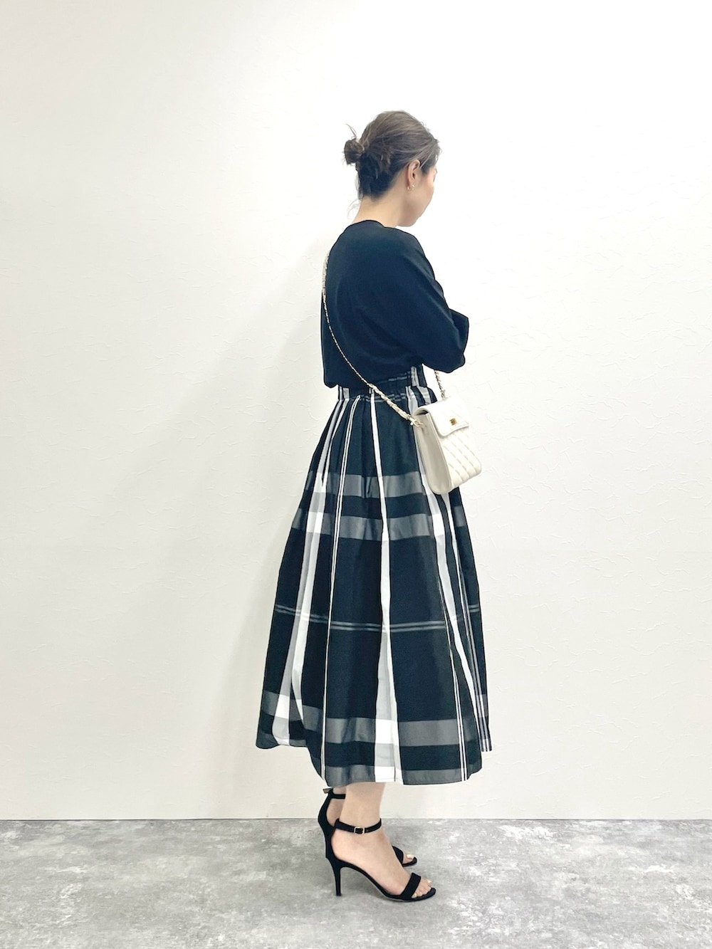 ブラック系のTシャツ/カットソー、ホワイト系のショルダーバッグ、ブラック系のスカートを着用したレディースの春コーディネートの3枚目の写真