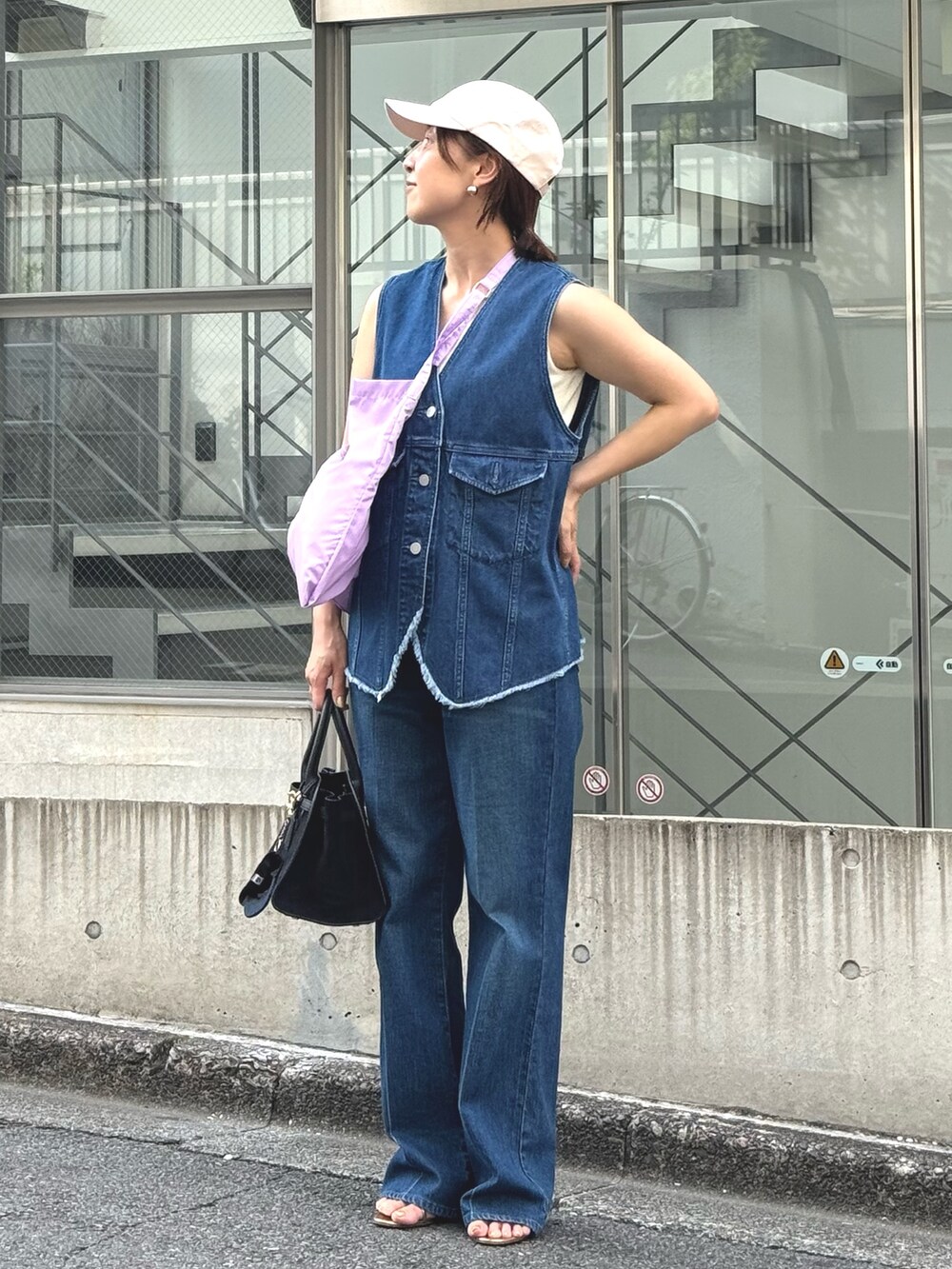 ブルー系のデニムパンツ、ブルー系のベスト、ブラック系のトートバッグを着用したレディースの夏コーディネートの3枚目の写真