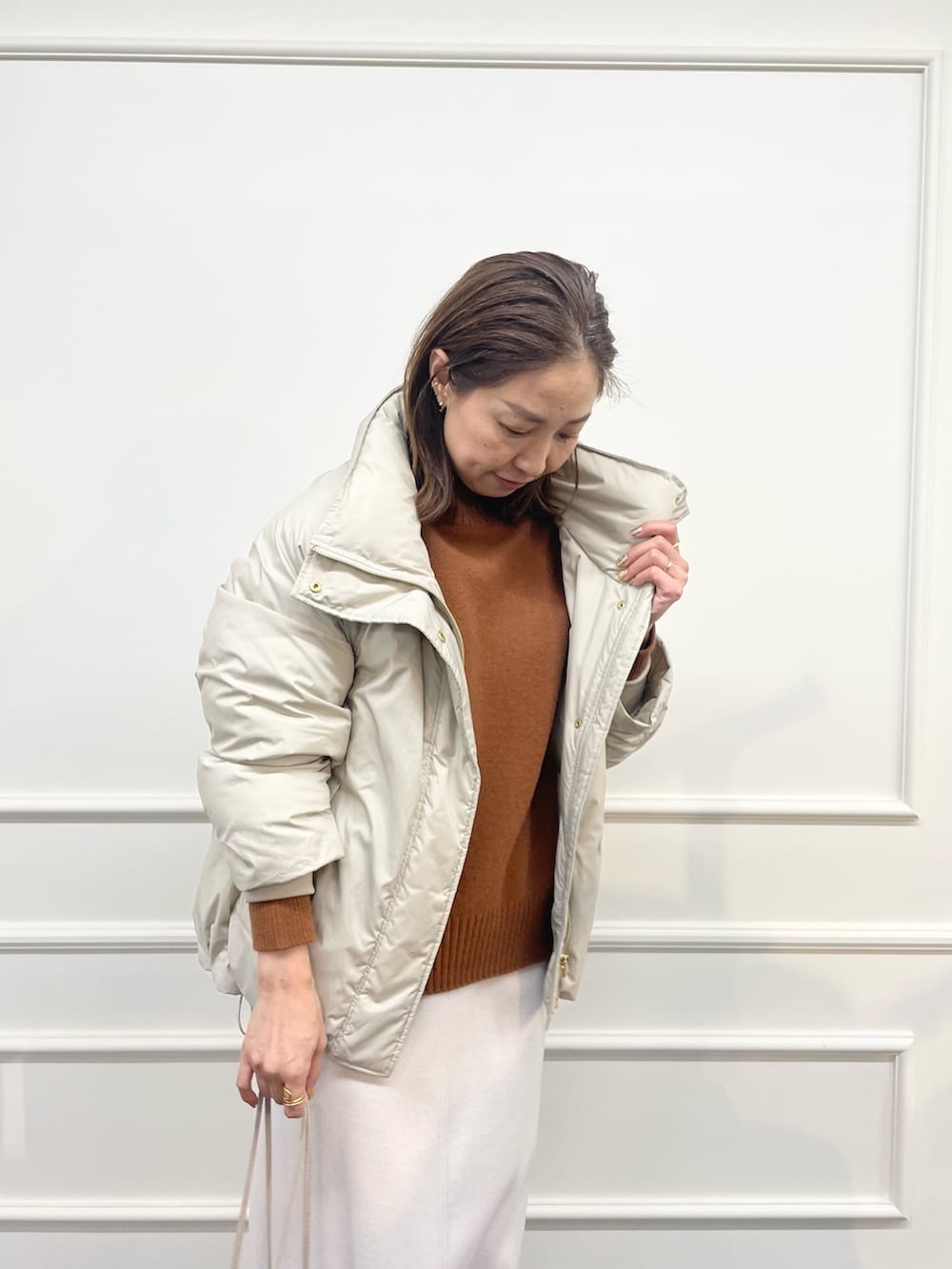 ベージュ系のダウンジャケット/コート、ブラウン系のニット/セーター、ベージュ系のスカートを着用したレディースの秋コーディネートの4枚目の写真