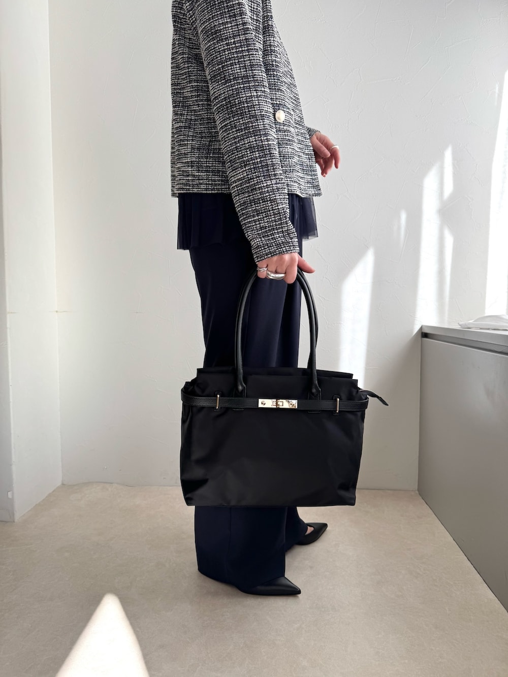 ブラック系のノーカラージャケット、ブルー系のシャツ/ブラウス、ブラック系のトートバッグを着用したレディースの春コーディネートの7枚目の写真