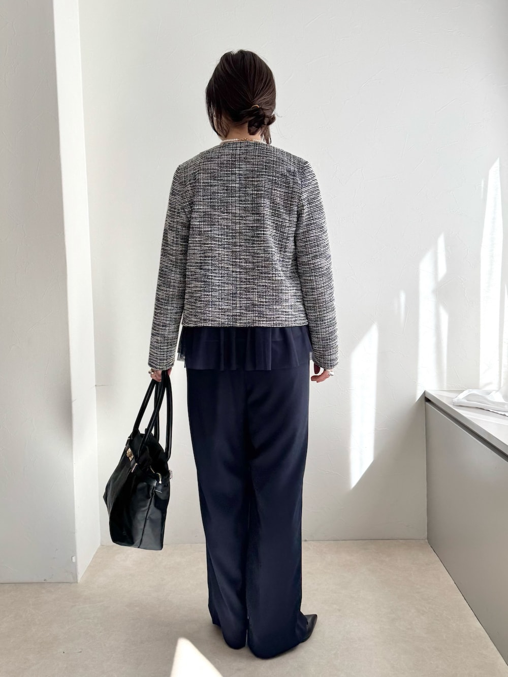 ブラック系のノーカラージャケット、ブルー系のシャツ/ブラウス、ブラック系のトートバッグを着用したレディースの春コーディネートの2枚目の写真