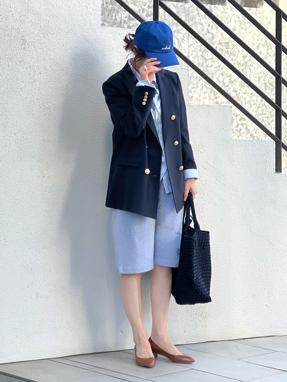 ブルー系のテーラードジャケット、ブルー系のトートバッグ、グレー系のスウェットパンツを着用したレディースの春コーディネートの2枚目の写真