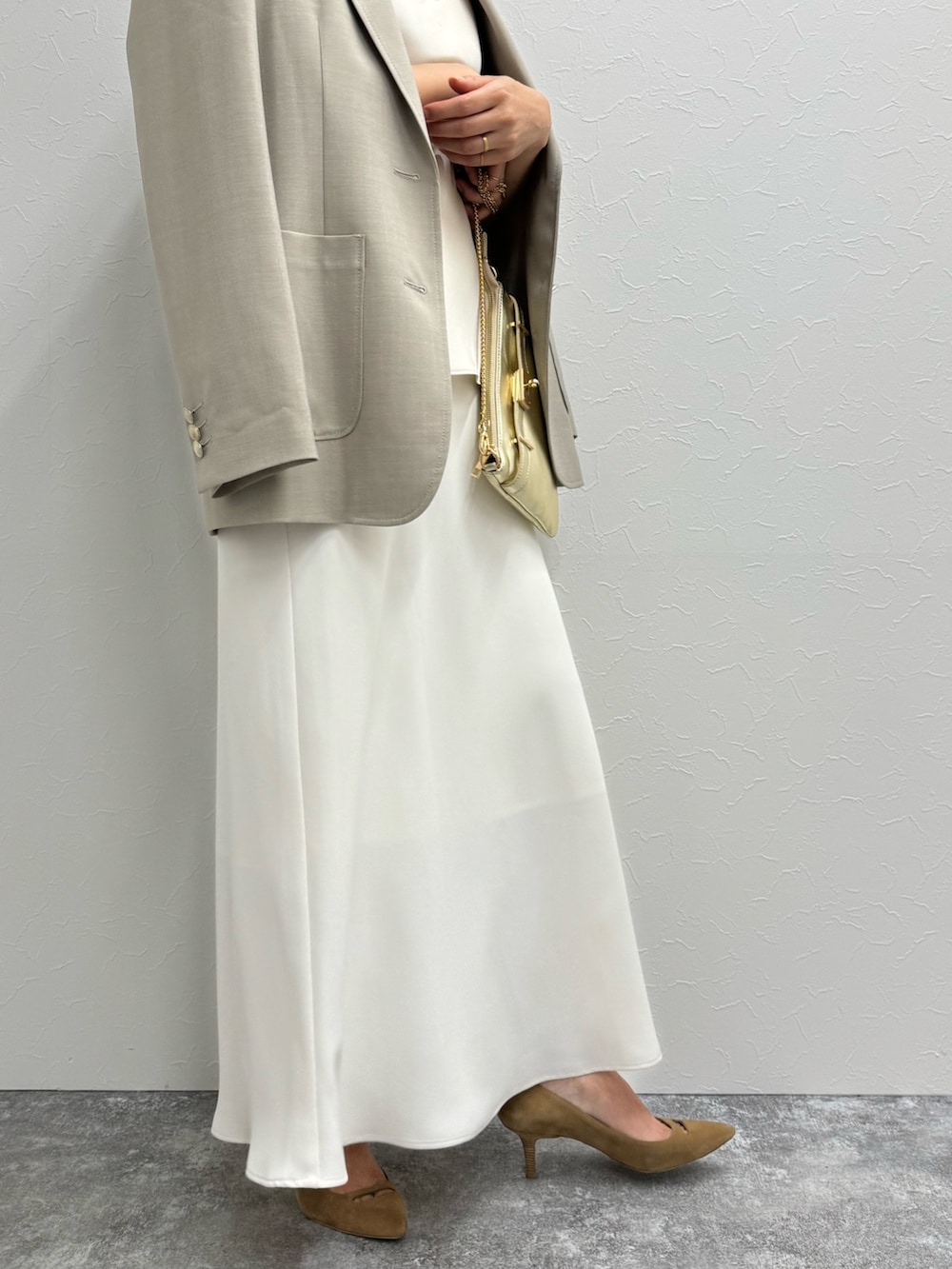 ベージュ系のテーラードジャケット、ベージュ系のタンクトップ、ホワイト系のスカートを着用したレディースの夏コーディネートの6枚目の写真