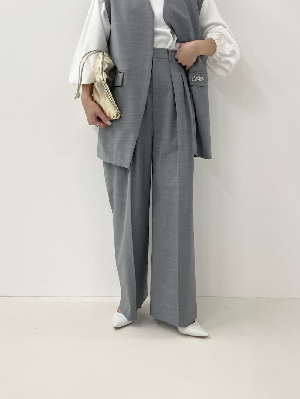 ゴールド系のショルダーバッグ、ホワイト系のTシャツ/カットソー、グレー系のベストを着用したレディースの冬コーディネートの8枚目の写真