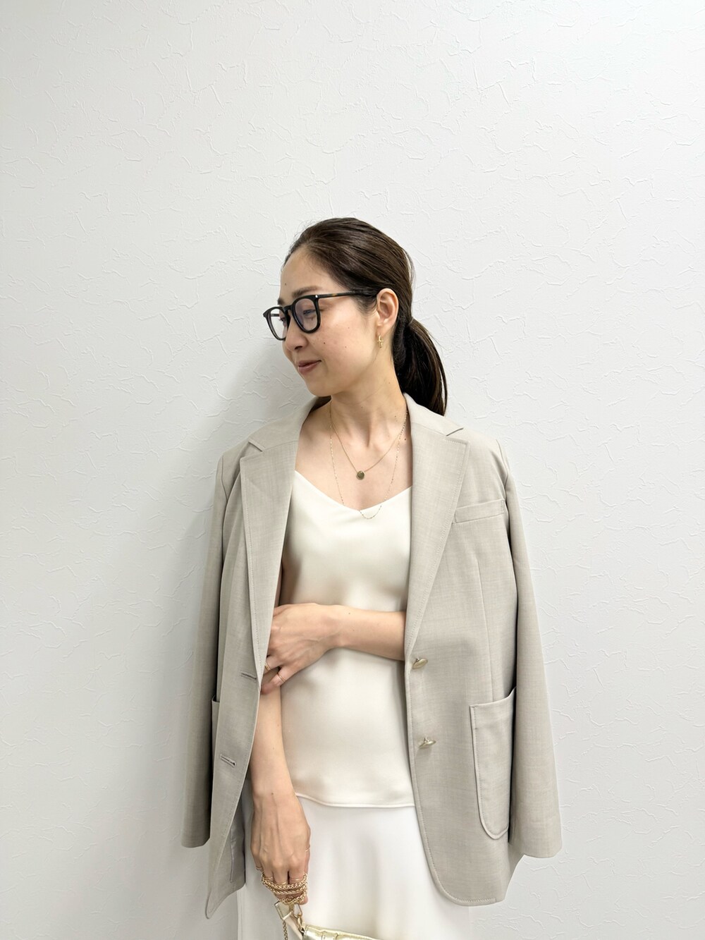 ベージュ系のテーラードジャケット、ベージュ系のタンクトップ、ホワイト系のスカートを着用したレディースの夏コーディネートの2枚目の写真