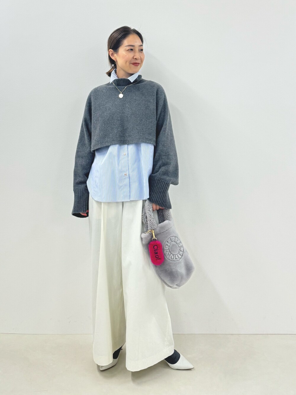 グレー系のニット/セーター、ブルー系のシャツ/ブラウス、ホワイト系のその他パンツを着用したレディースの秋コーディネートの3枚目の写真