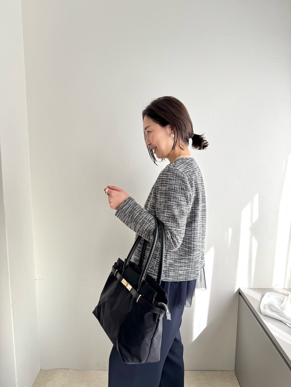 ブラック系のノーカラージャケット、ブルー系のシャツ/ブラウス、ブラック系のトートバッグを着用したレディースの春コーディネートの4枚目の写真