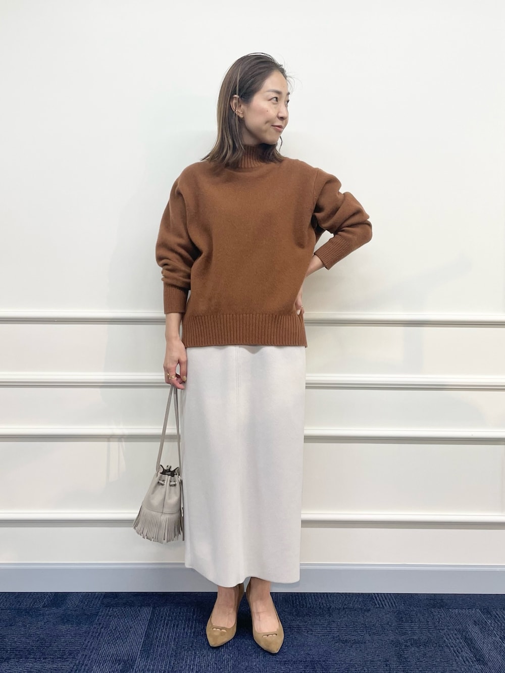 ベージュ系のダウンジャケット/コート、ブラウン系のニット/セーター、ベージュ系のスカートを着用したレディースの秋コーディネートの6枚目の写真