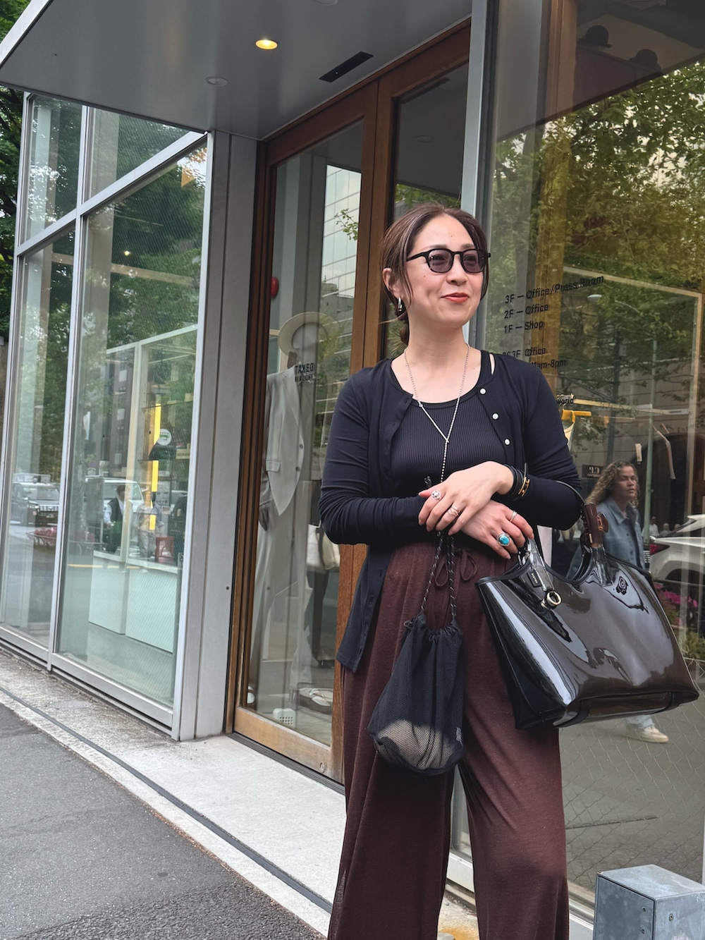 ブラウン系のその他パンツ、ブラック系のカーディガン/ボレロ、シルバー系のネックレスを着用したレディースの夏コーディネートの9枚目の写真