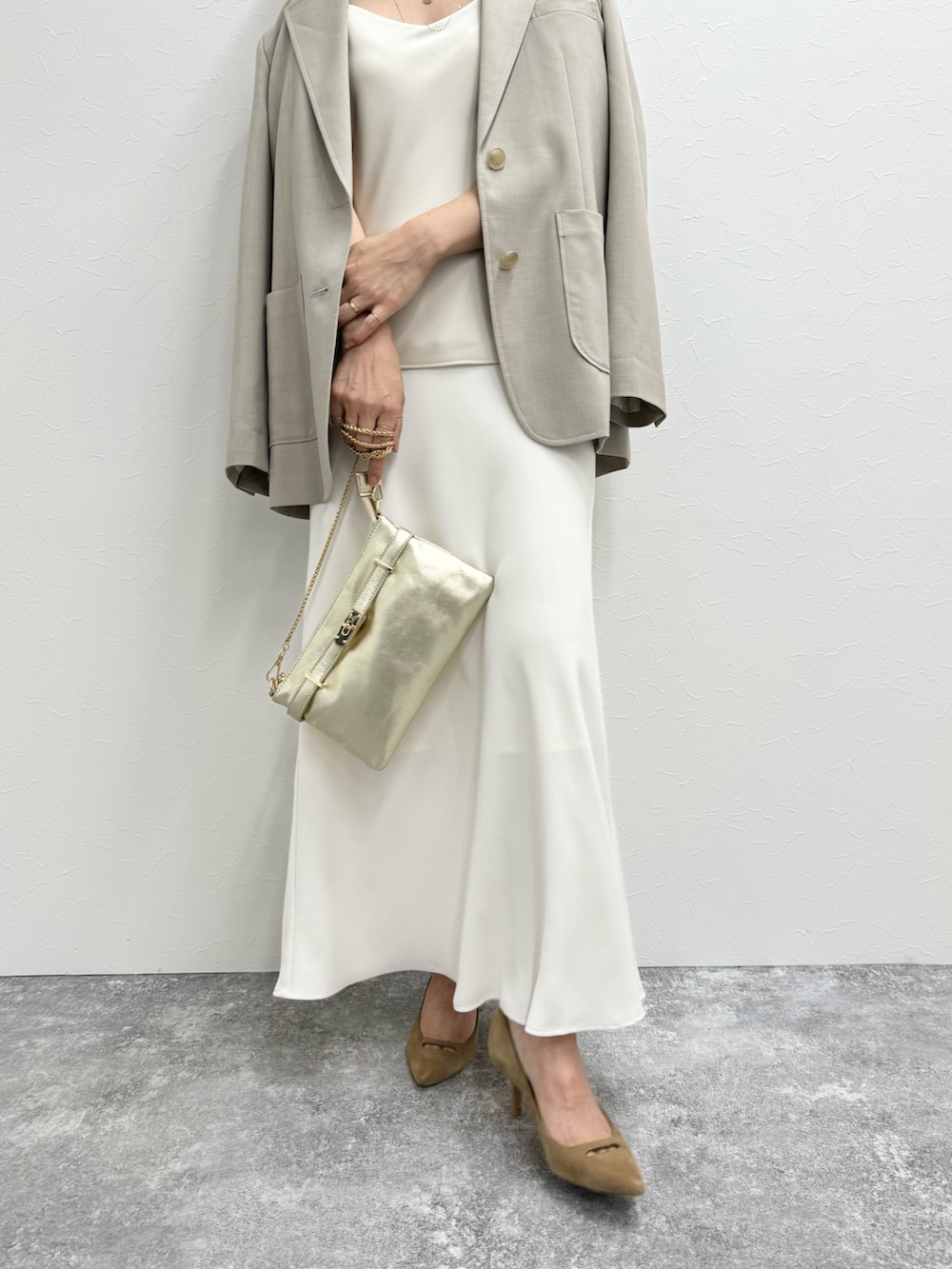 ベージュ系のテーラードジャケット、ベージュ系のタンクトップ、ホワイト系のスカートを着用したレディースの夏コーディネートの4枚目の写真