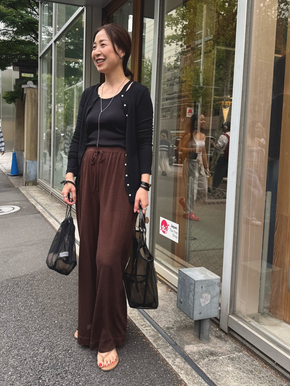 ブラウン系のその他パンツ、ブラック系のカーディガン/ボレロ、シルバー系のネックレスを着用したレディースの夏コーディネートの4枚目の写真