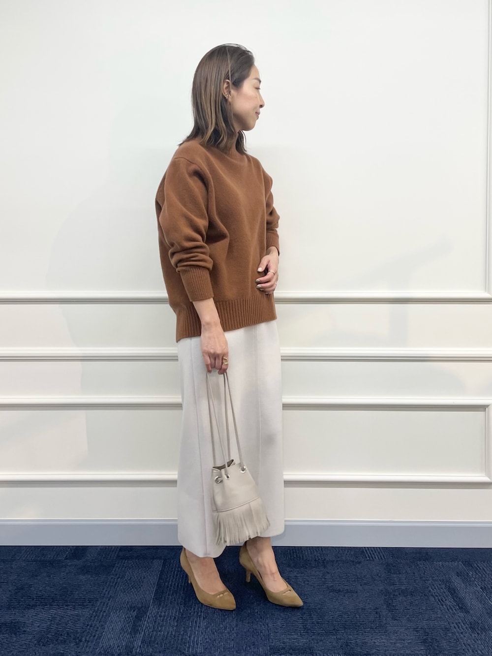 ベージュ系のダウンジャケット/コート、ブラウン系のニット/セーター、ベージュ系のスカートを着用したレディースの秋コーディネートの7枚目の写真