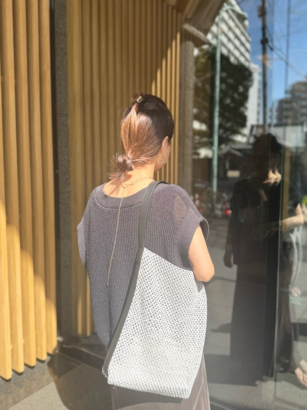 ブラウン系のスカート、ブラック系のベスト、グレー系のショルダーバッグを着用したレディースの夏コーディネートの4枚目の写真