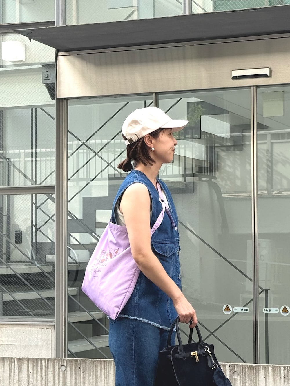 ブルー系のデニムパンツ、ブルー系のベスト、ブラック系のトートバッグを着用したレディースの夏コーディネートの9枚目の写真