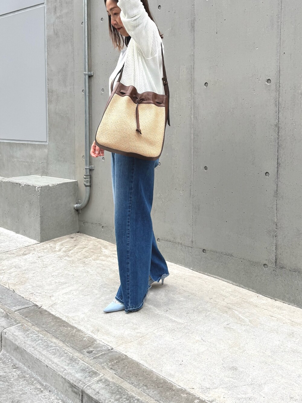 ブルー系のデニムパンツ、ブラウン系のショルダーバッグ、ホワイト系のカーディガン/ボレロを着用したレディースの春コーディネートの3枚目の写真