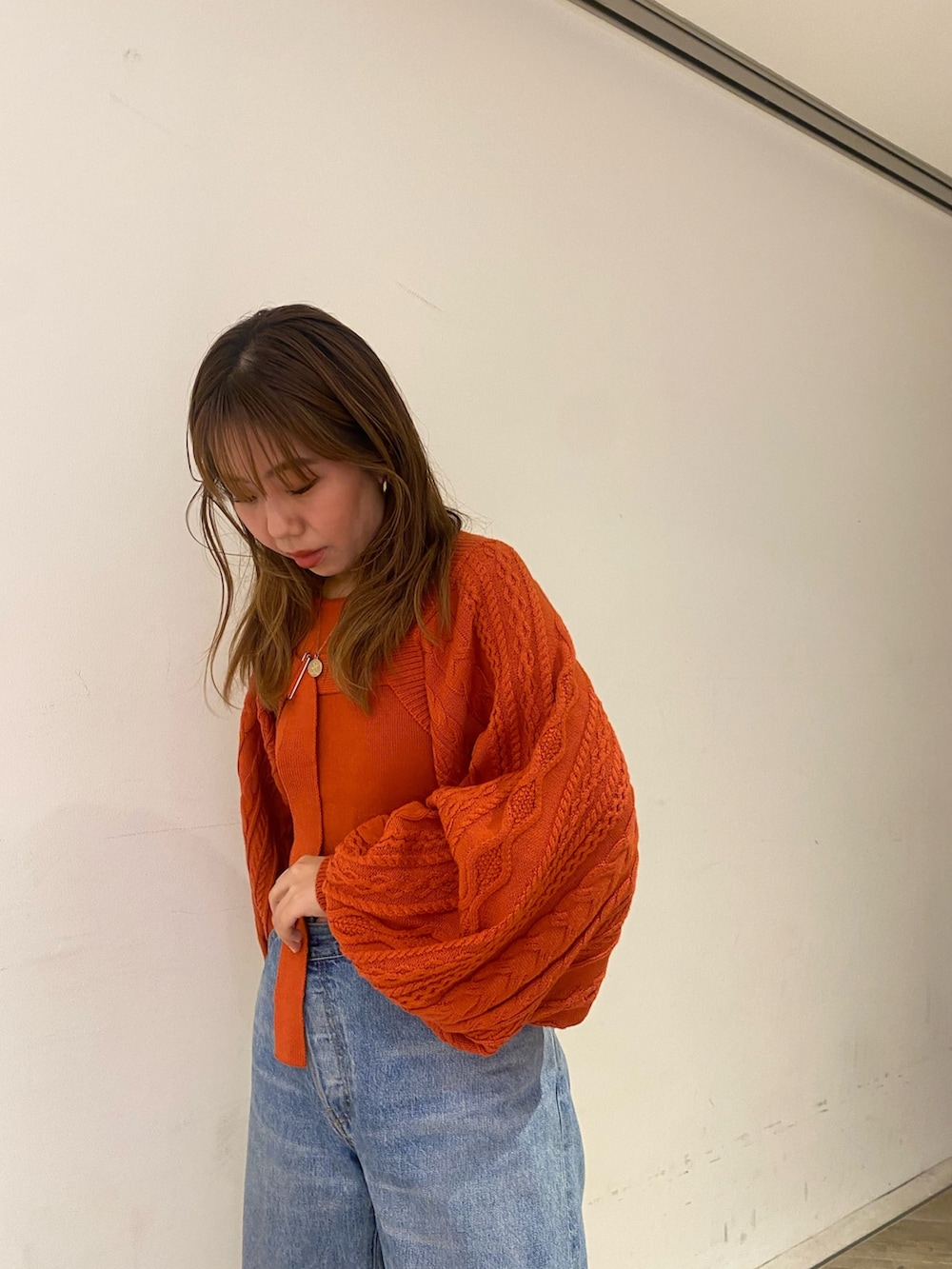 オレンジ系のカーディガン/ボレロ、ブルー系のデニムパンツ、ブラック系のブーツを着用したレディースの秋コーディネートの5枚目の写真