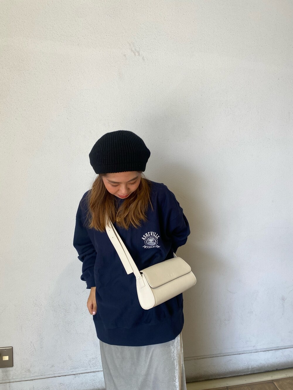 ブルー系のスウェット、グレー系のスカート、ホワイト系のショルダーバッグを着用したレディースの秋コーディネートの3枚目の写真