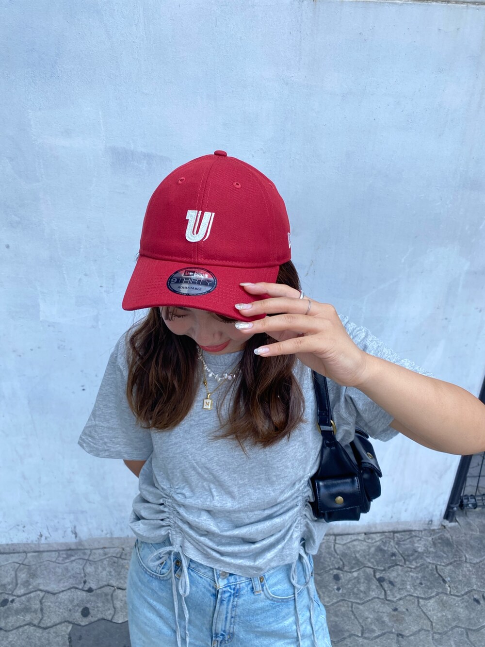 グレー系のTシャツ/カットソー、ブルー系のデニムパンツ、ブラック系のハンドバッグを着用したレディースの夏コーディネートの5枚目の写真