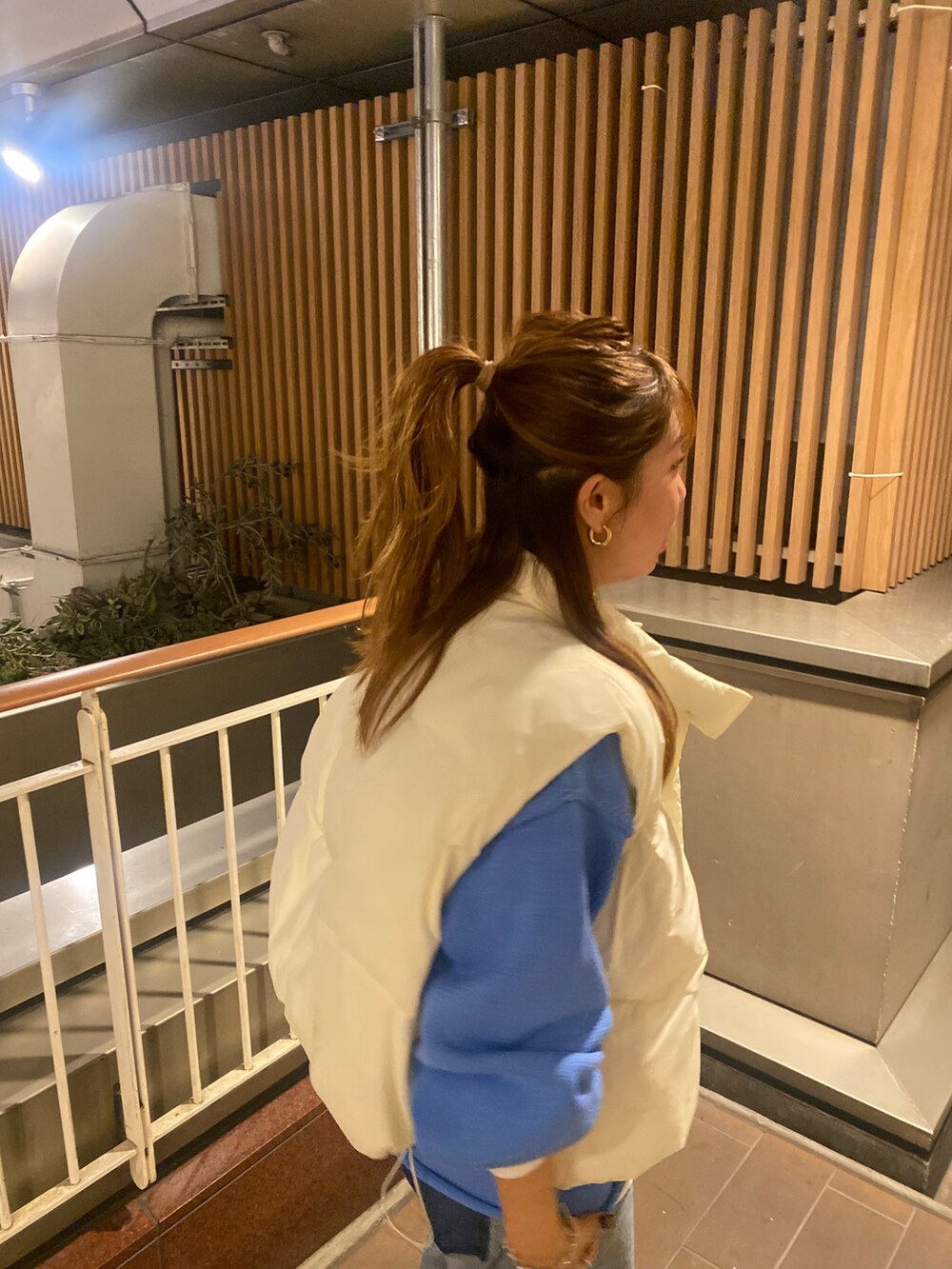 ホワイト系のダウンベスト、ブルー系のニット/セーター、ブルー系のデニムパンツを着用したレディースの秋コーディネートの6枚目の写真