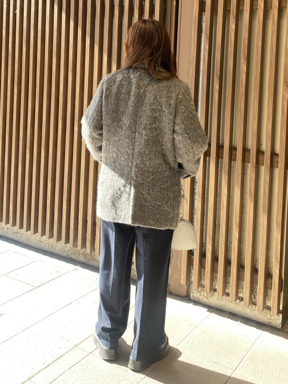 グレー系のテーラードジャケット、グレー系のニット/セーター、シルバー系のショルダーバッグを着用したレディースの冬コーディネートの3枚目の写真