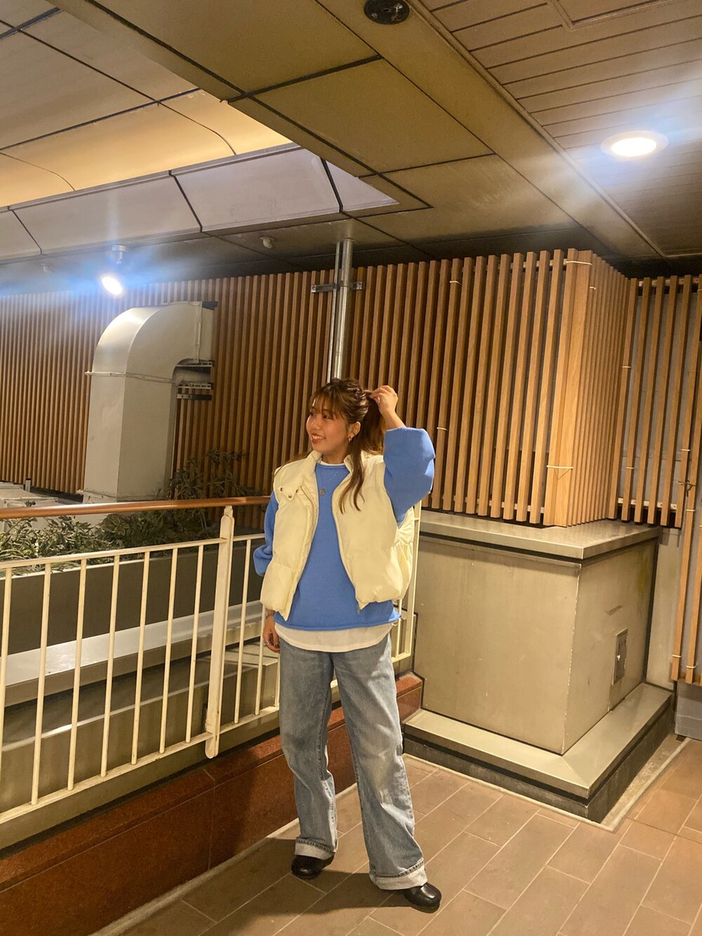 ホワイト系のダウンベスト、ブルー系のニット/セーター、ブルー系のデニムパンツを着用したレディースの秋コーディネートの7枚目の写真