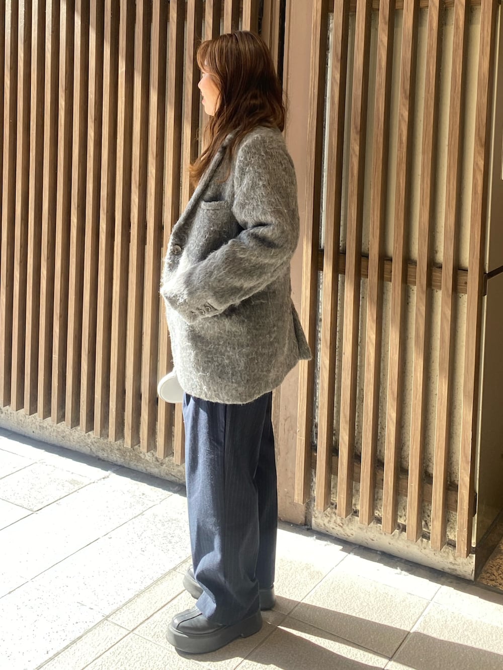 グレー系のテーラードジャケット、グレー系のニット/セーター、シルバー系のショルダーバッグを着用したレディースの冬コーディネートの2枚目の写真