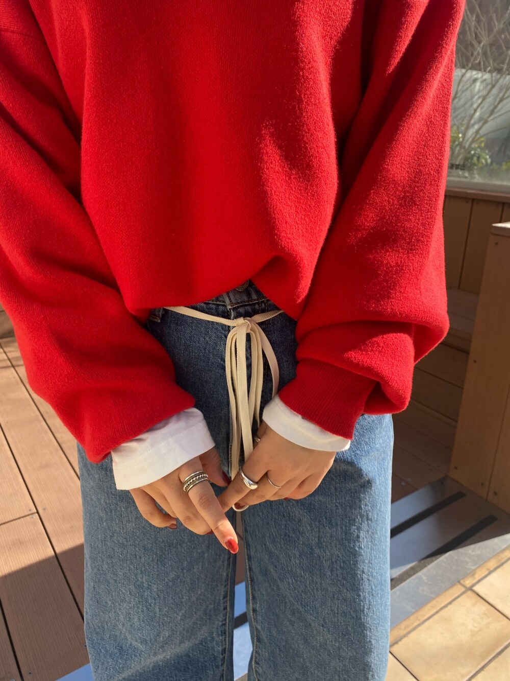 その他のチェスターコート、ブルー系のデニムパンツ、レッド系のニット/セーターを着用したレディースの冬コーディネートの5枚目の写真