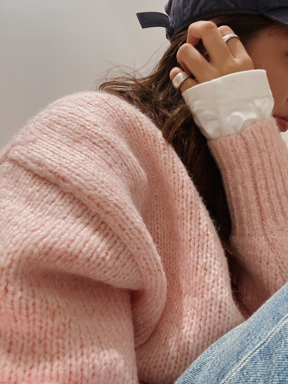 ピンク系のニット/セーター、ホワイト系のTシャツ/カットソー、ブルー系のデニムパンツを着用したレディースの秋コーディネートの3枚目の写真