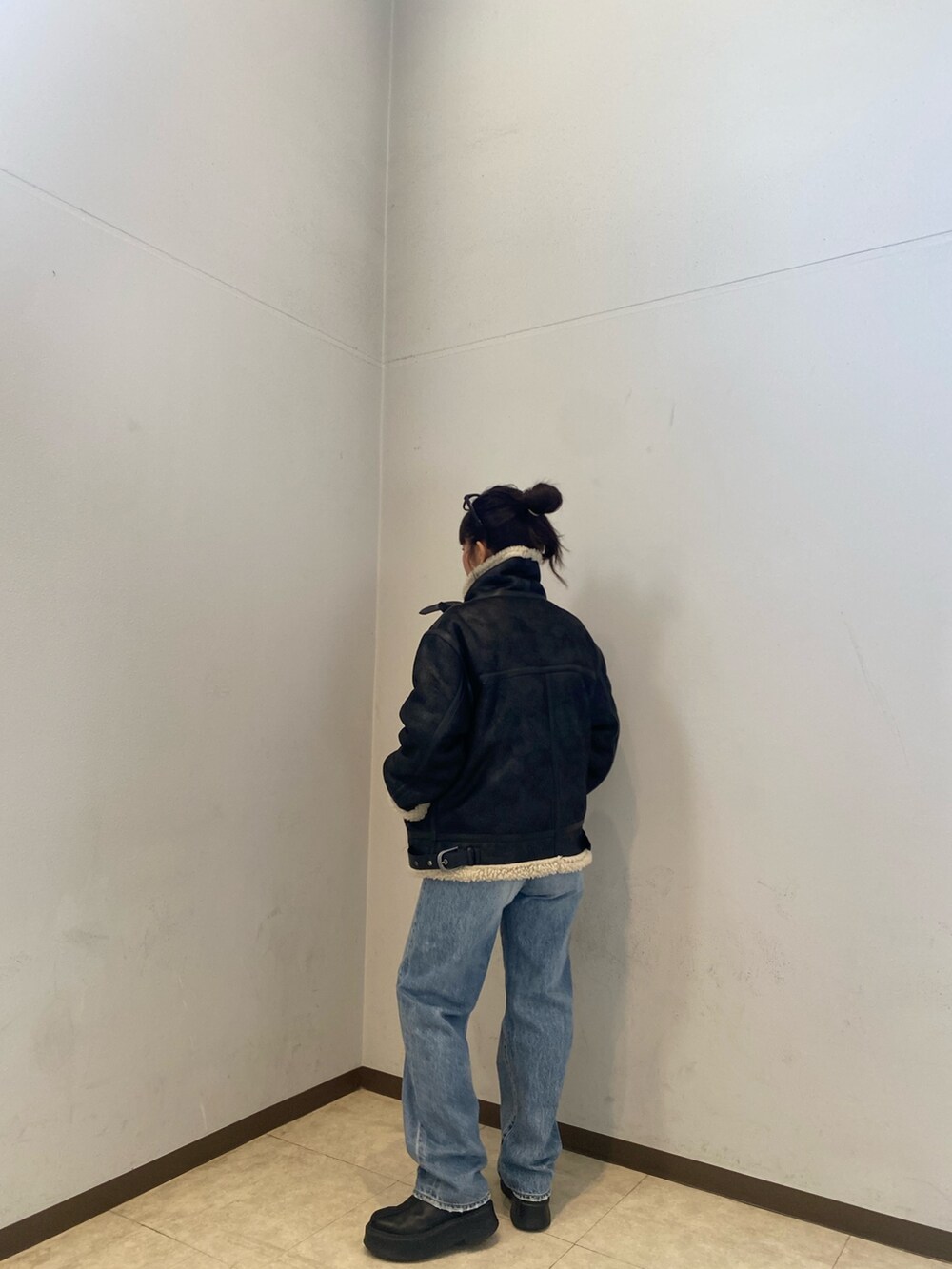 ブラック系のムートンコート、ブルー系のデニムパンツを着用したレディースの冬コーディネートの4枚目の写真