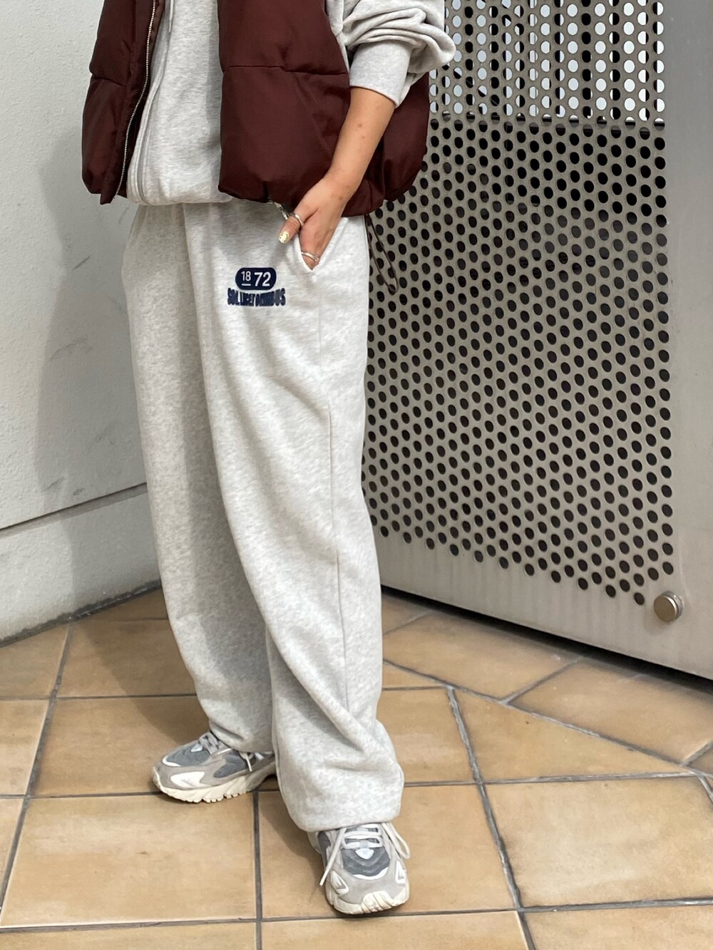 ブラウン系のダウンベスト、グレー系のスウェットパンツ、グレー系のパーカーを着用したレディースの秋コーディネートの6枚目の写真