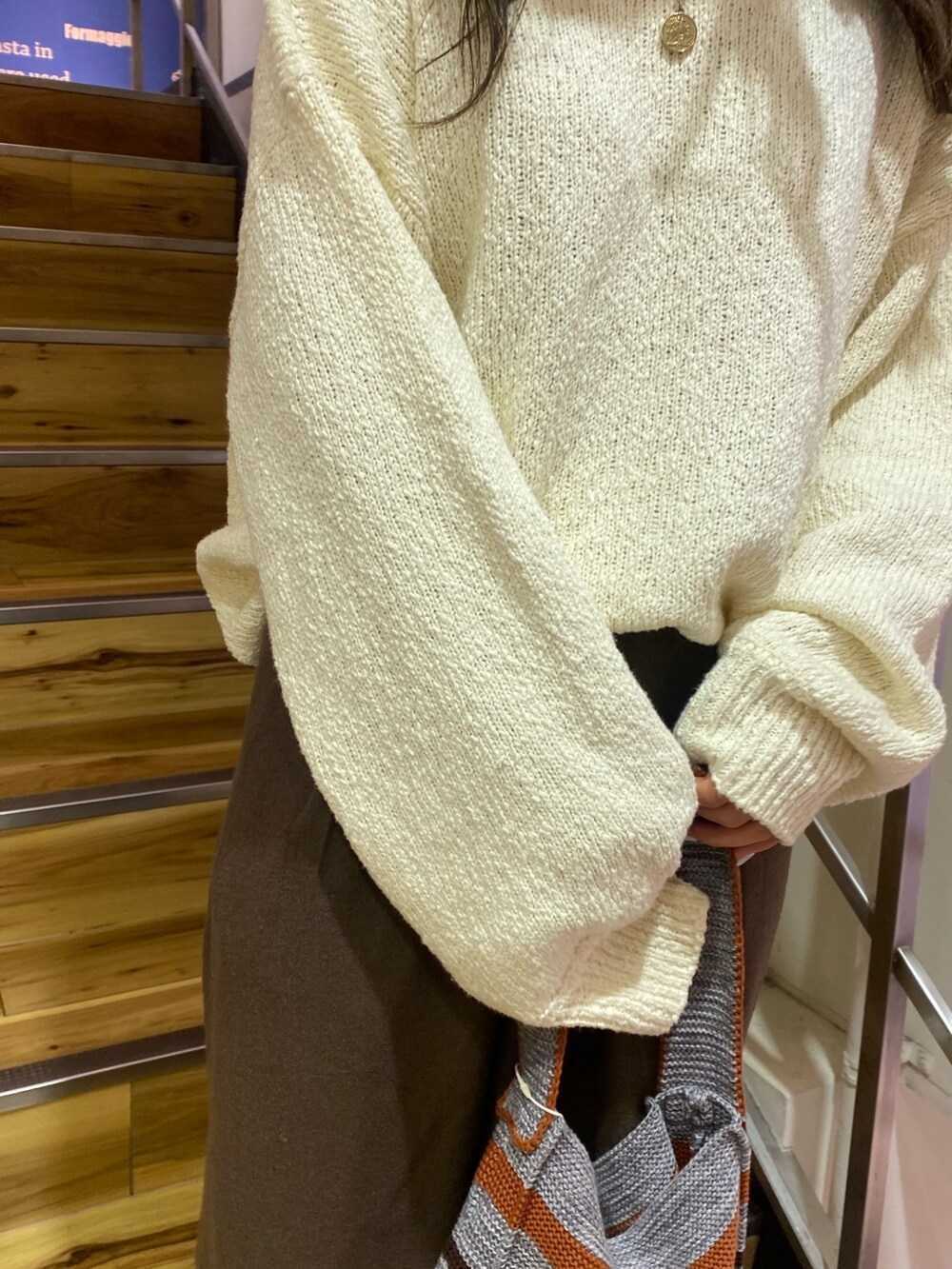 ホワイト系のニット/セーター、ブラウン系のその他パンツ、グレー系のハンドバッグを着用したレディースの冬コーディネートの7枚目の写真