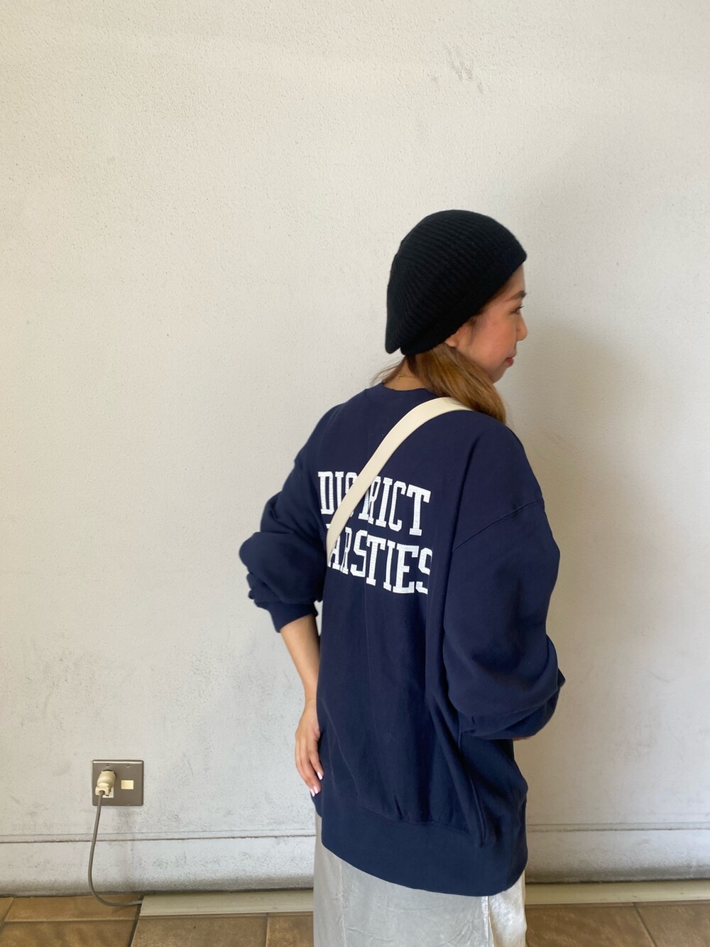 ブルー系のスウェット、グレー系のスカート、ホワイト系のショルダーバッグを着用したレディースの秋コーディネートの4枚目の写真