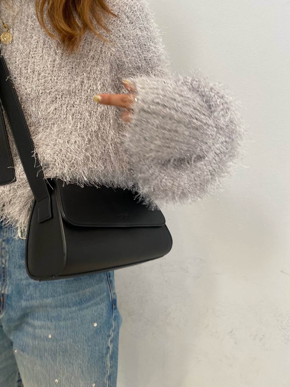 ブラック系のニット/セーター、ブルー系のデニムパンツ、ブラウン系のブーツを着用したレディースの秋コーディネートの5枚目の写真