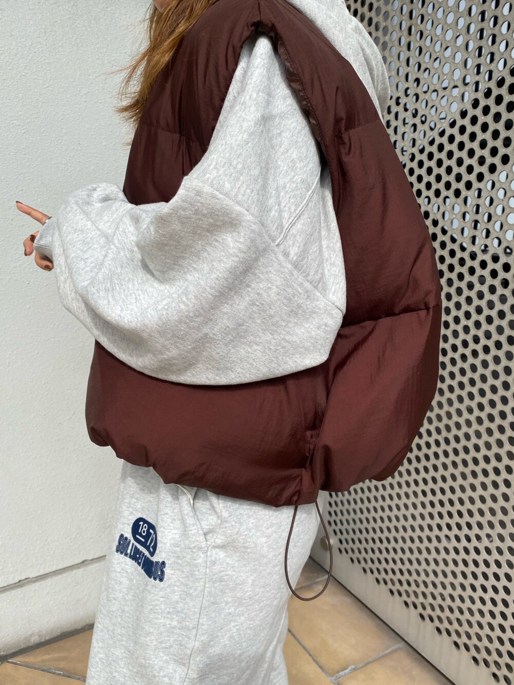 ブラウン系のダウンベスト、グレー系のスウェットパンツ、グレー系のパーカーを着用したレディースの秋コーディネートの3枚目の写真