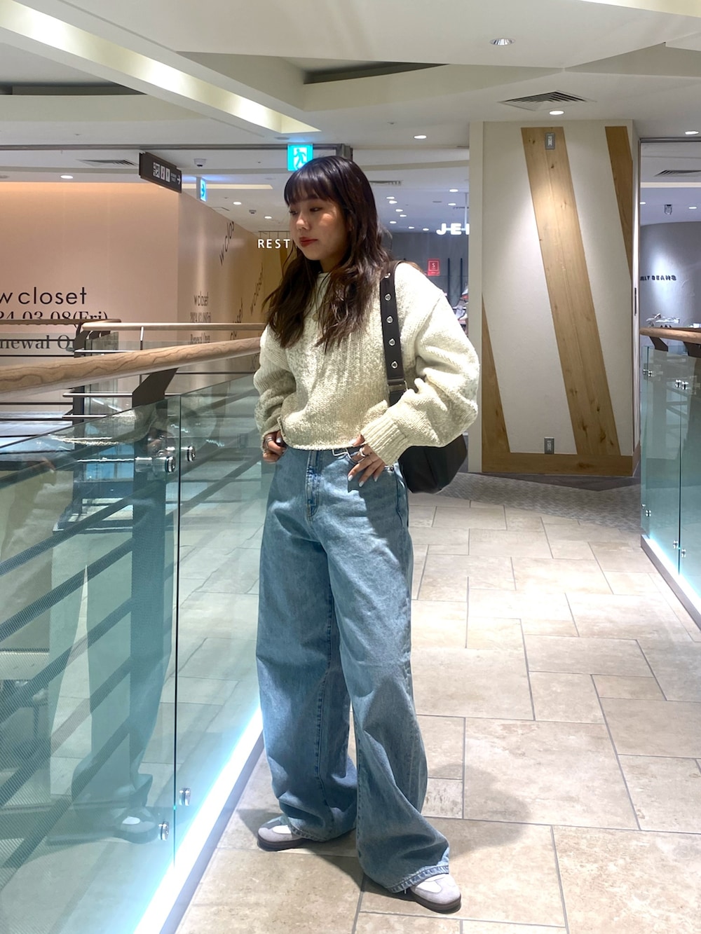 ホワイト系のニット/セーター、ブルー系のデニムパンツ、ブラウン系のショルダーバッグを着用したレディースの冬コーディネートの2枚目の写真