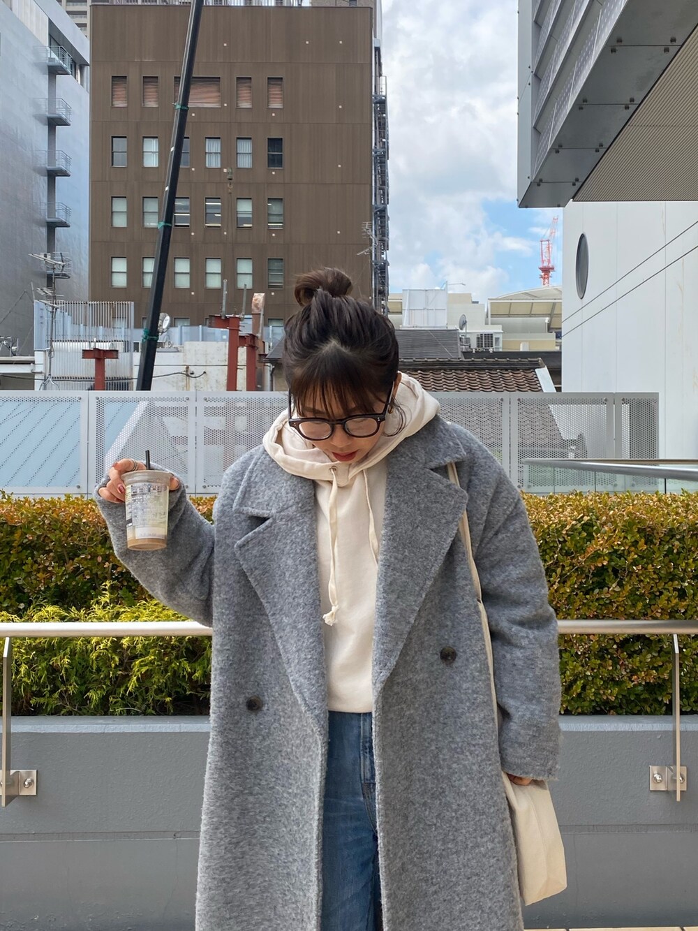 グレー系のチェスターコート、ホワイト系のパーカー、ブルー系のデニムパンツを着用したレディースの冬コーディネートの4枚目の写真