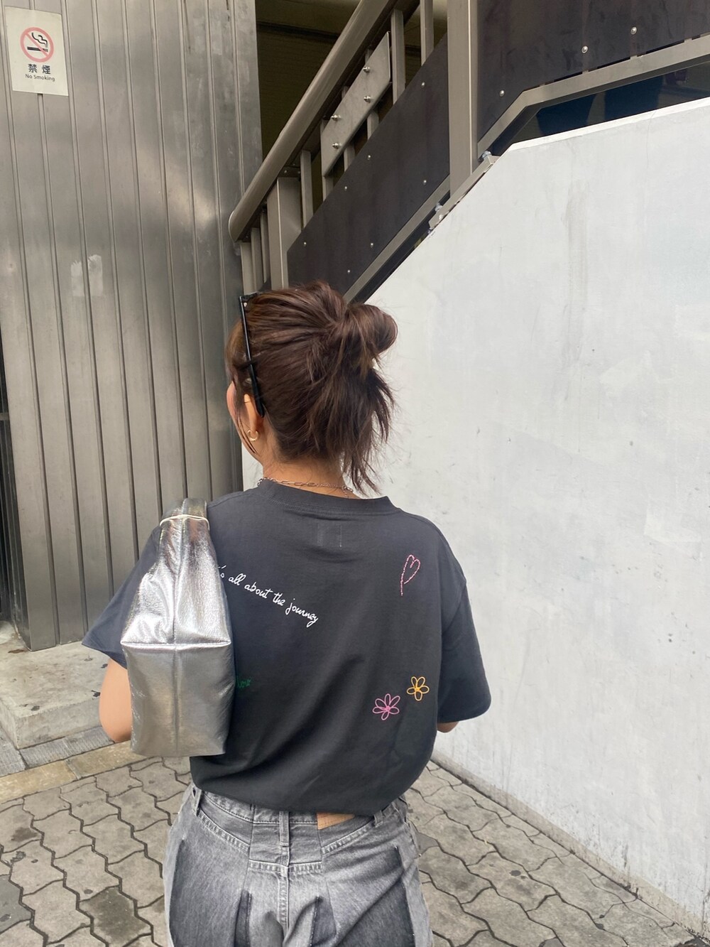 グレー系のTシャツ/カットソー、ブラック系のデニムパンツ、シルバー系のサンダルを着用したレディースの春コーディネートの5枚目の写真