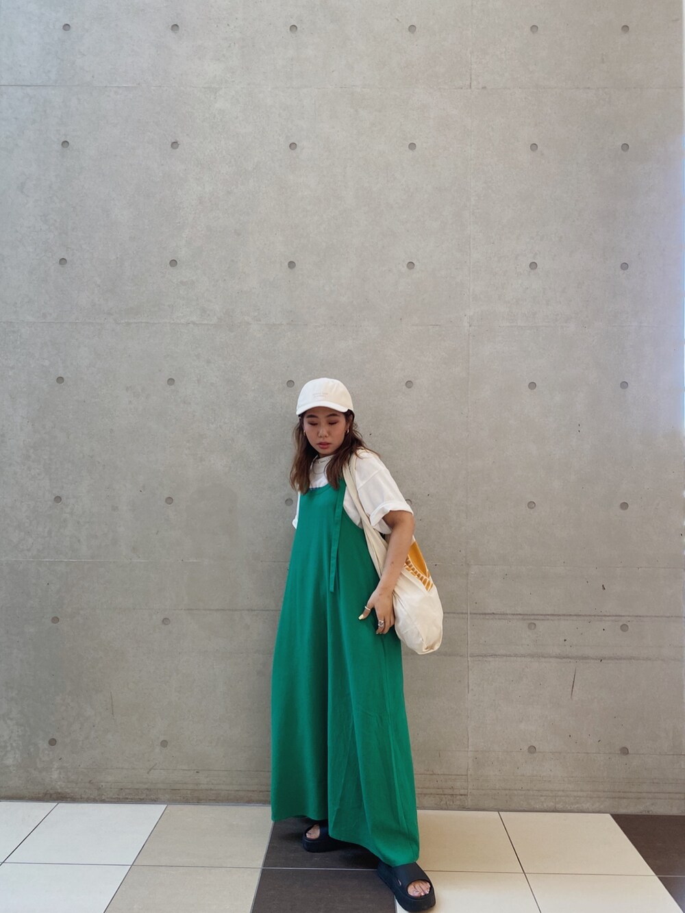 グリーン系のワンピース、ホワイト系のキャップを着用したレディースの夏コーディネートの2枚目の写真