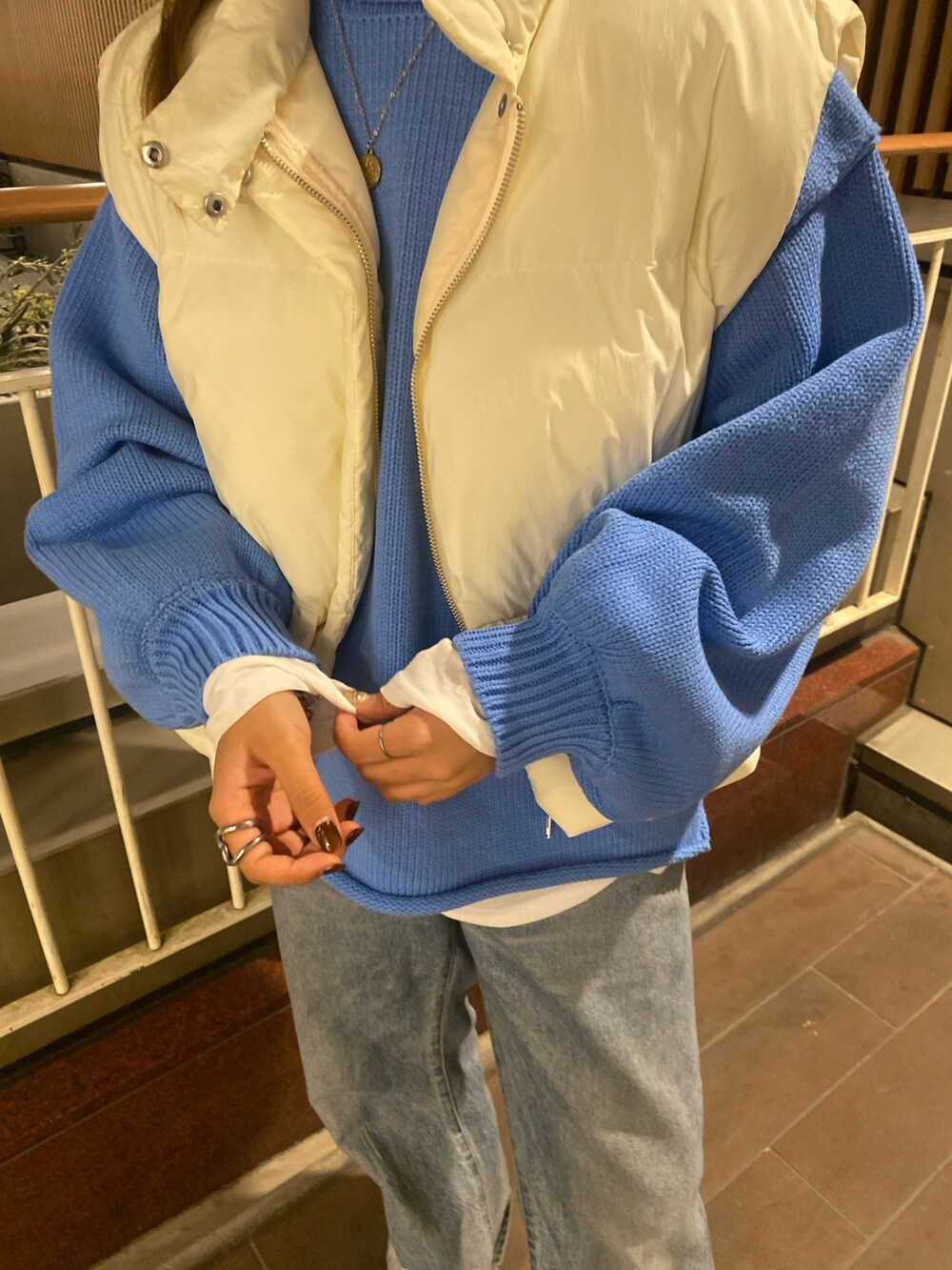 ホワイト系のダウンベスト、ブルー系のニット/セーター、ブルー系のデニムパンツを着用したレディースの秋コーディネートの5枚目の写真