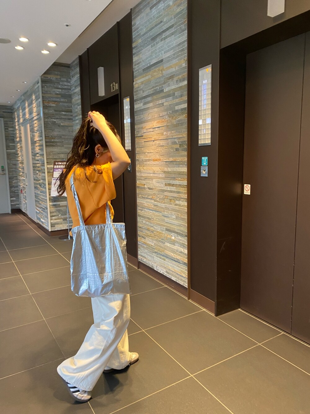 オレンジ系のTシャツ/カットソー、ホワイト系のデニムパンツを着用したレディースの春コーディネートの5枚目の写真