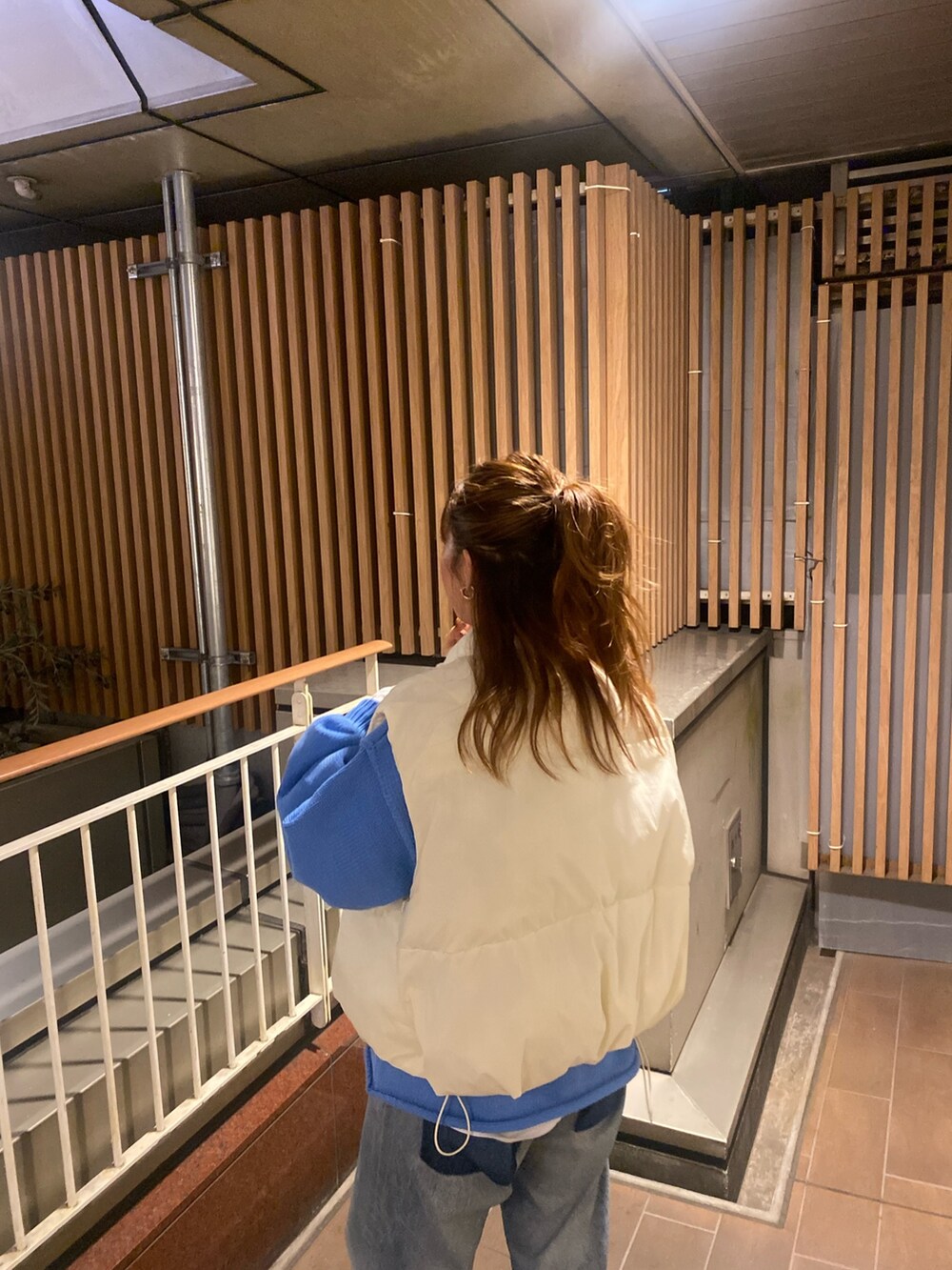 ホワイト系のダウンベスト、ブルー系のニット/セーター、ブルー系のデニムパンツを着用したレディースの秋コーディネートの4枚目の写真