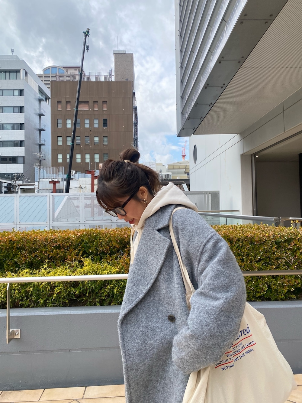 グレー系のチェスターコート、ホワイト系のパーカー、ブルー系のデニムパンツを着用したレディースの冬コーディネートの5枚目の写真